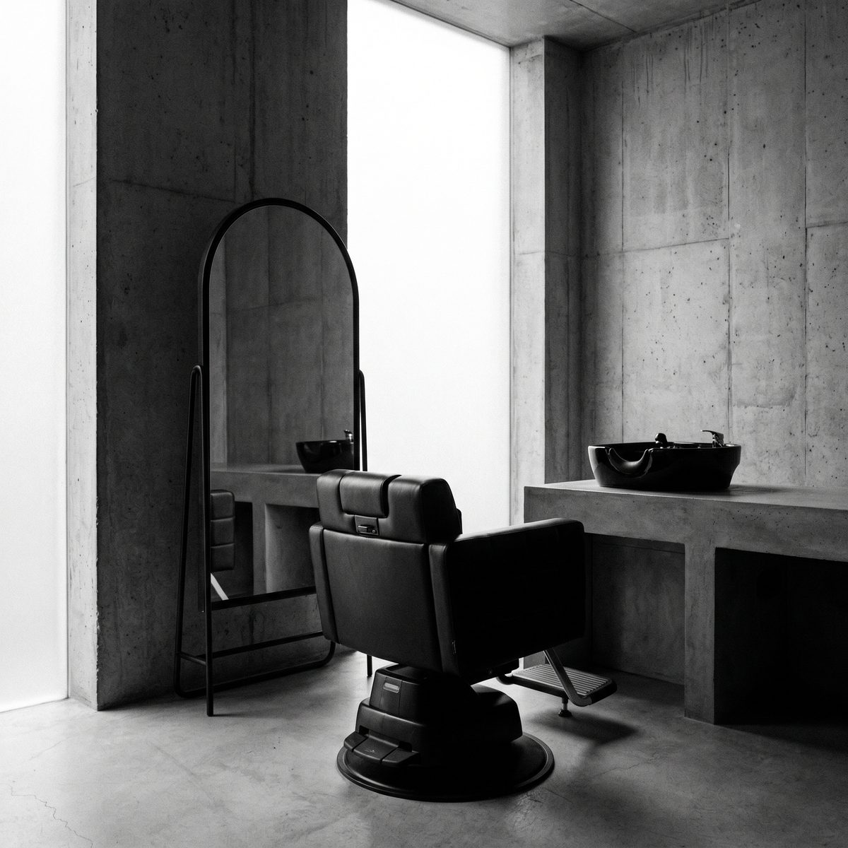 Fauteuil de coupe face au miroir arqué, murs en béton brut